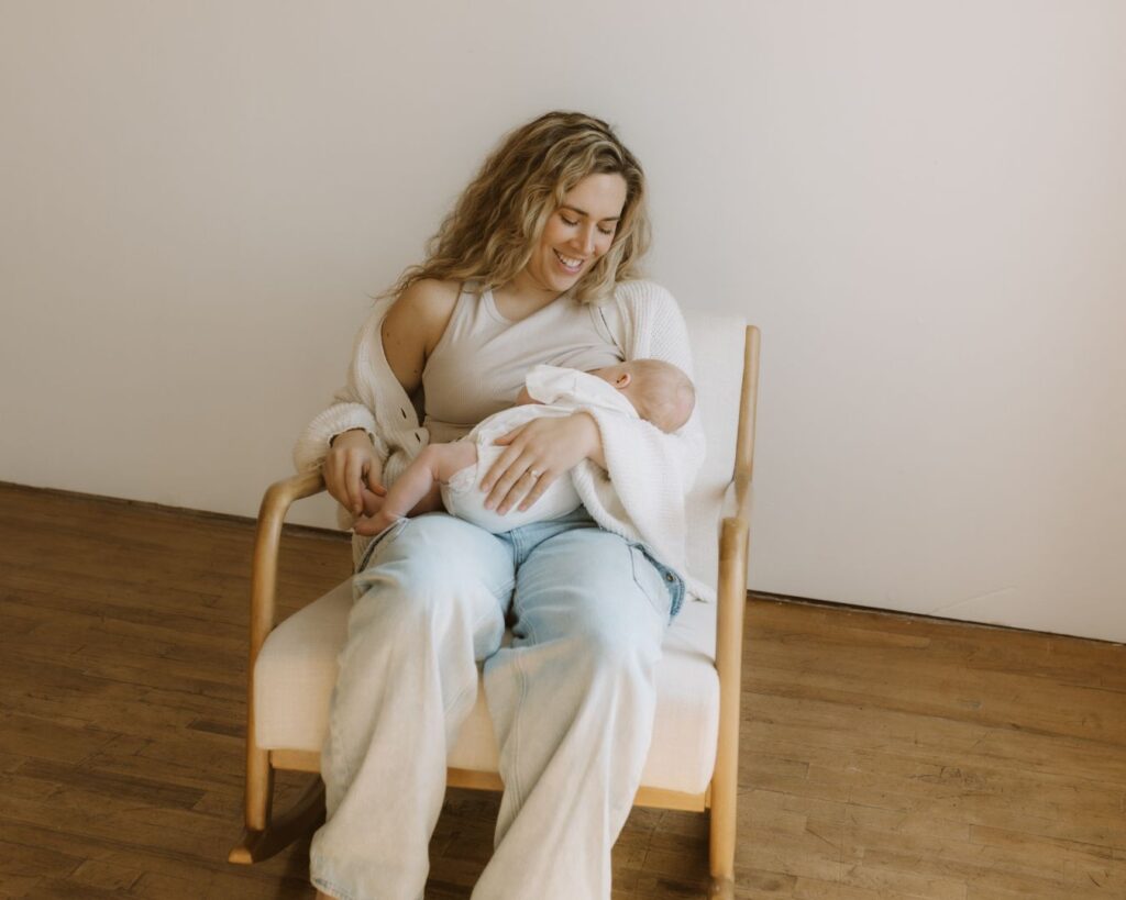 New mother breastfeeds newborn baby with smile on her face as she looks down at her child