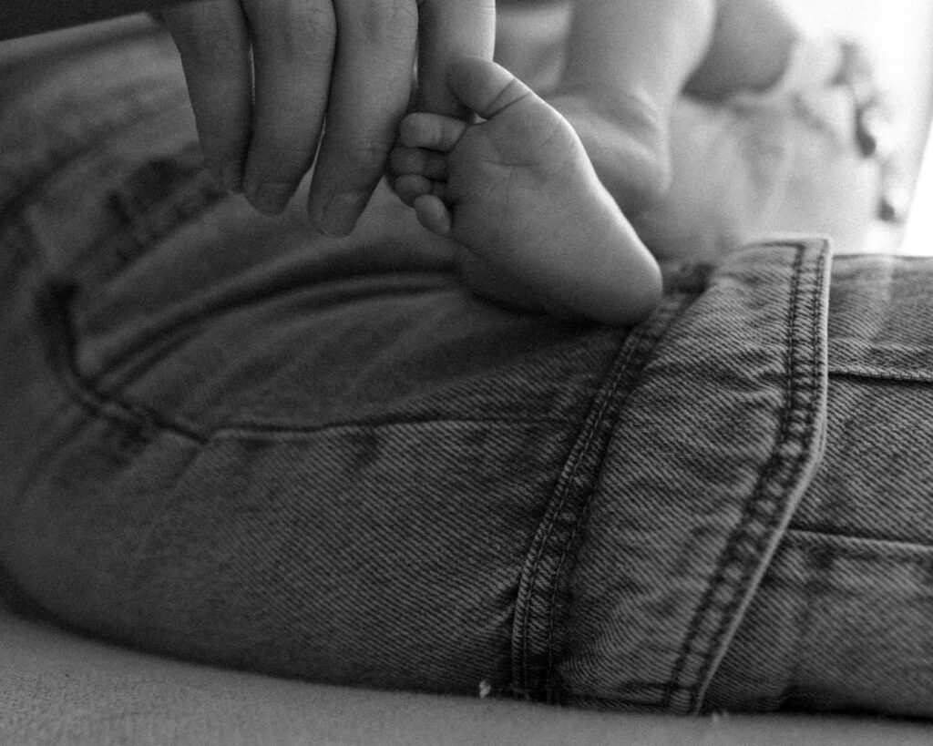 Black and white photograph of new mom caressing baby's toes