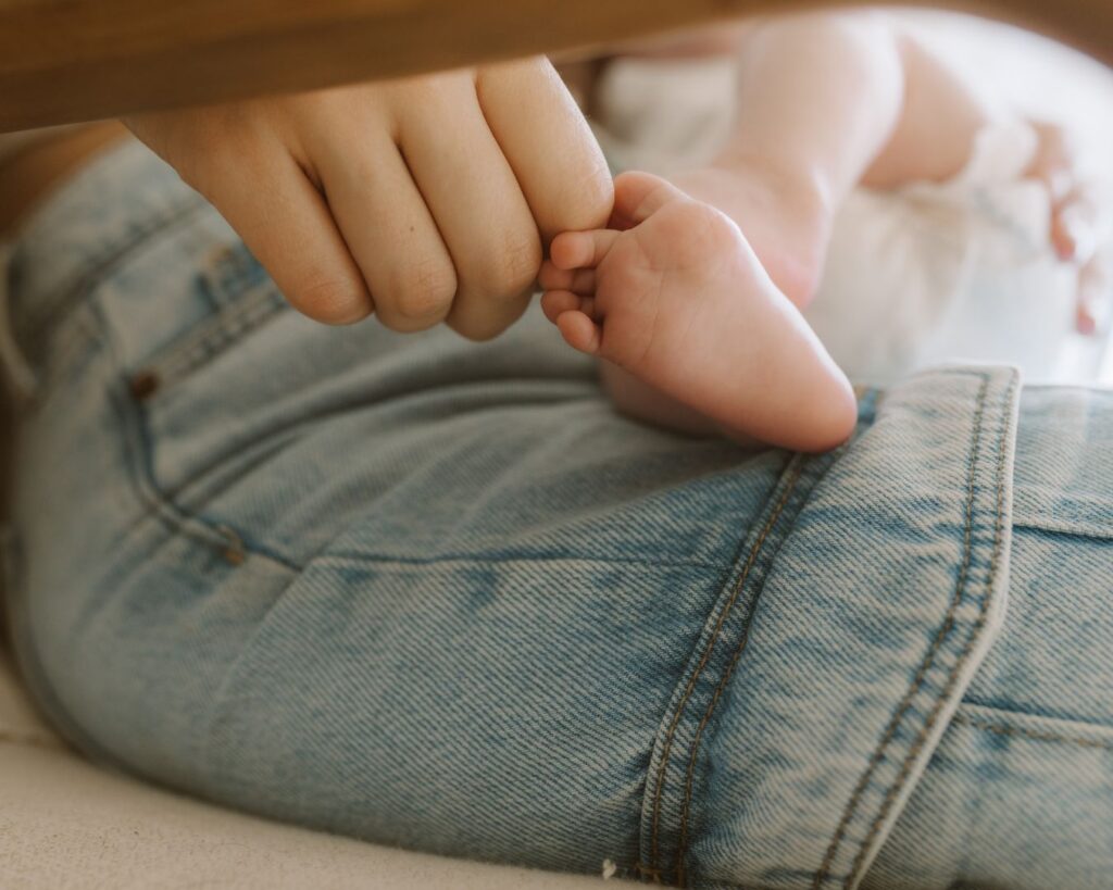 Mom touches newborn baby's little toes in family photoshoot 