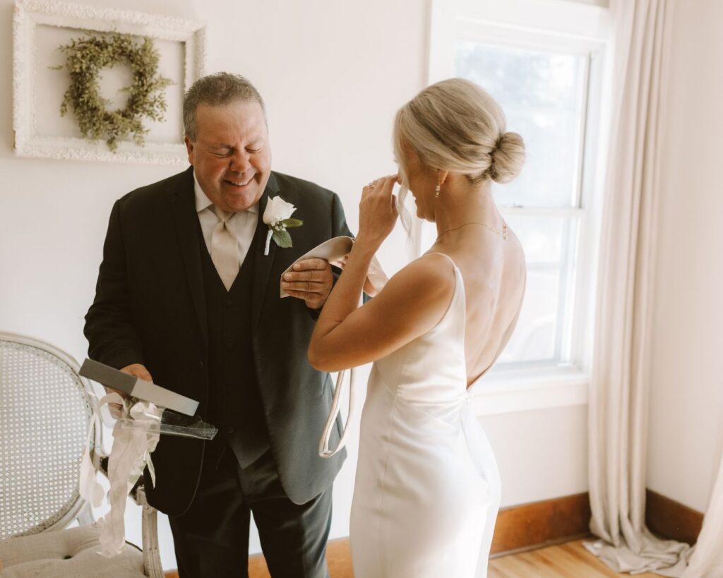 The bride and her father crying after she gave him a new tie with an image of the two of them when she was little on the back of it