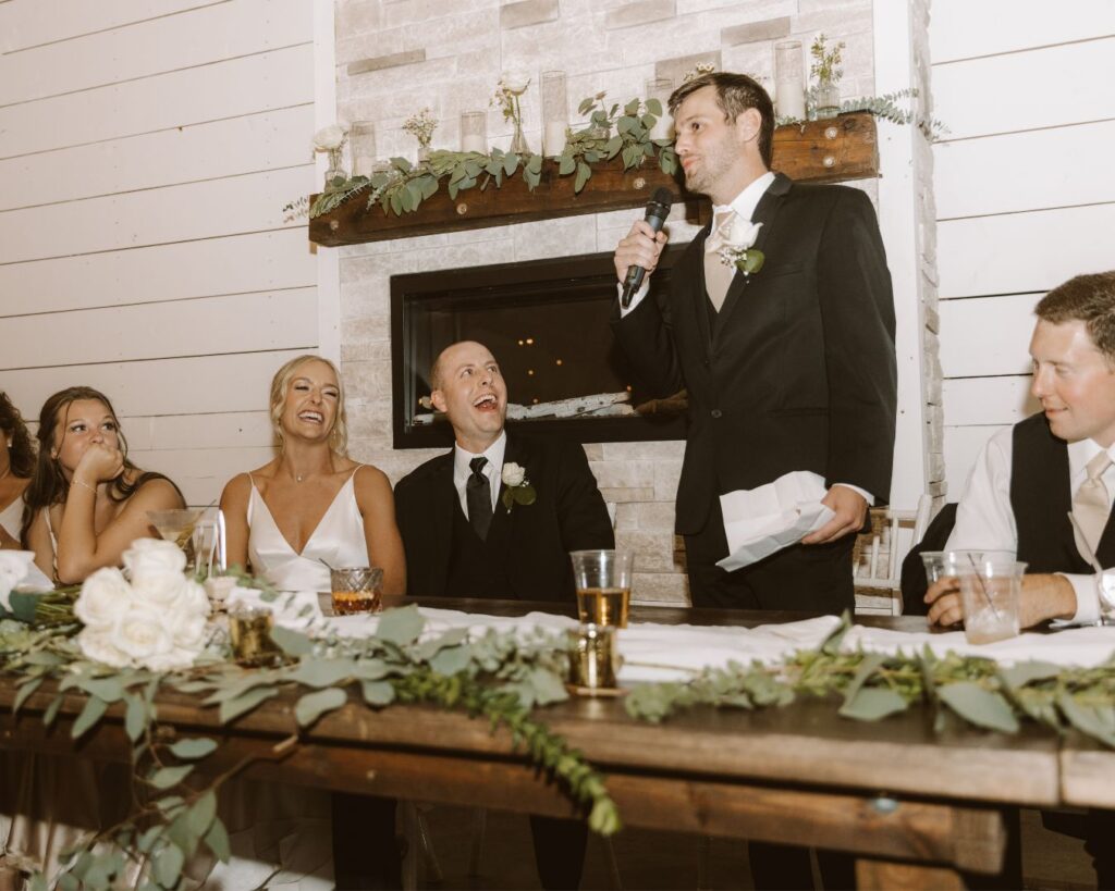 The bride and groom laughing at something the groom's brother said during his speech. 