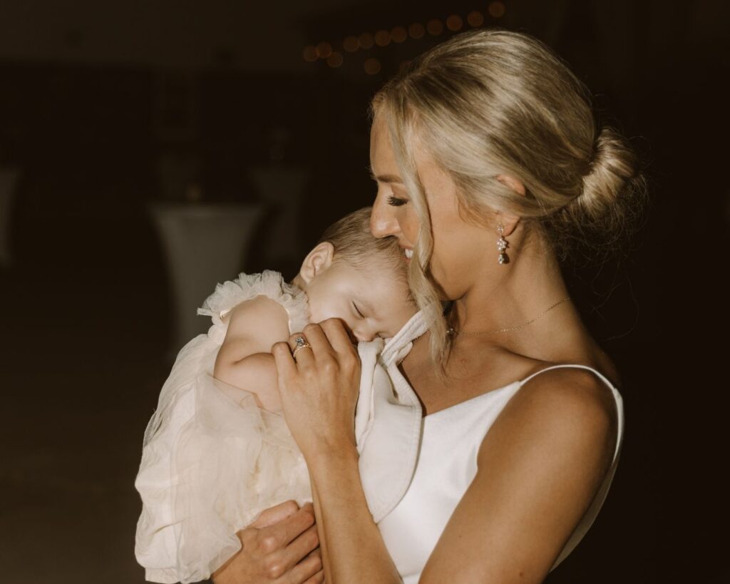 The bride holding her baby niece outside in the dark while she sleeps listening to the party inside.