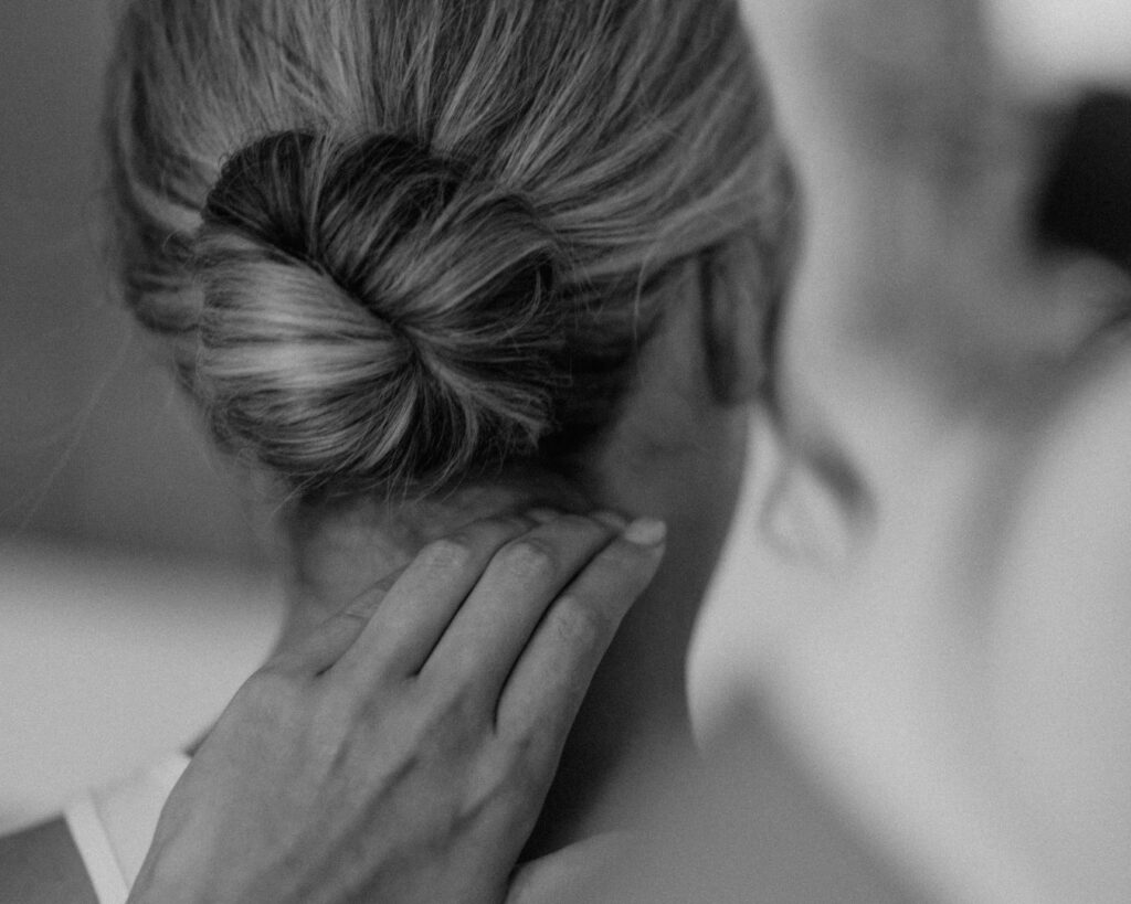 Black and white close up image of the hair artist finishing the bride's perfect ballet bun. 