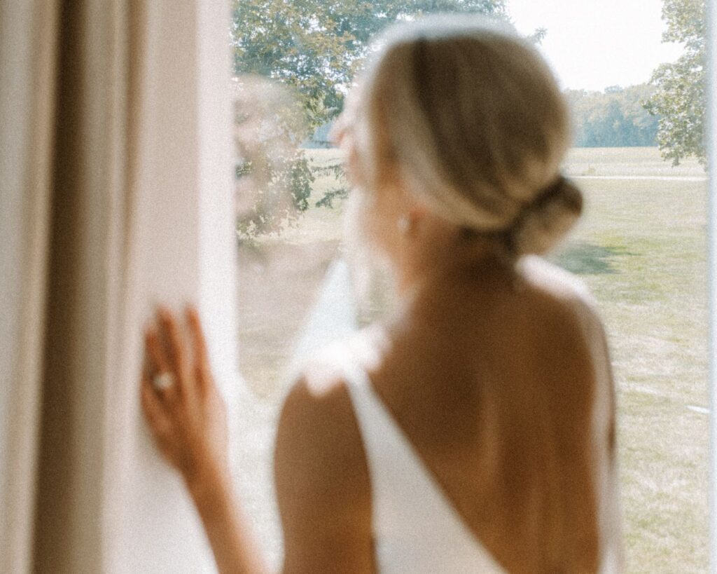 A blurry image of the bride looking out the window and laughing on her wedding day. 