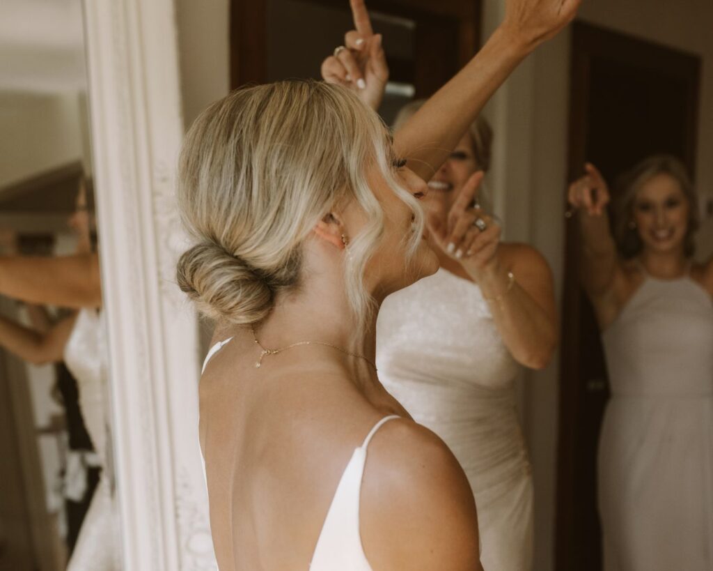 The bride dancing in the bridal suite with her mom and bridesmaids