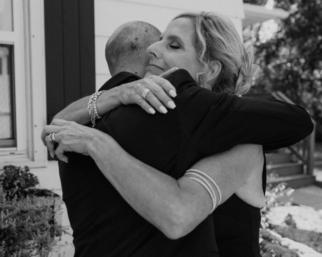 Black and white image of the groom hugging his mom after seeing each other all dressed up for the first time on his wedding day.