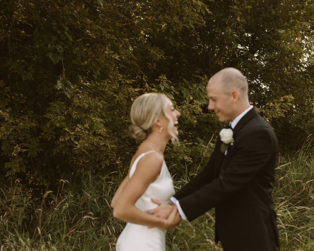 The bride and groom holding hands and smiling really big at each other after seeing one another for the first time on their wedding day. 