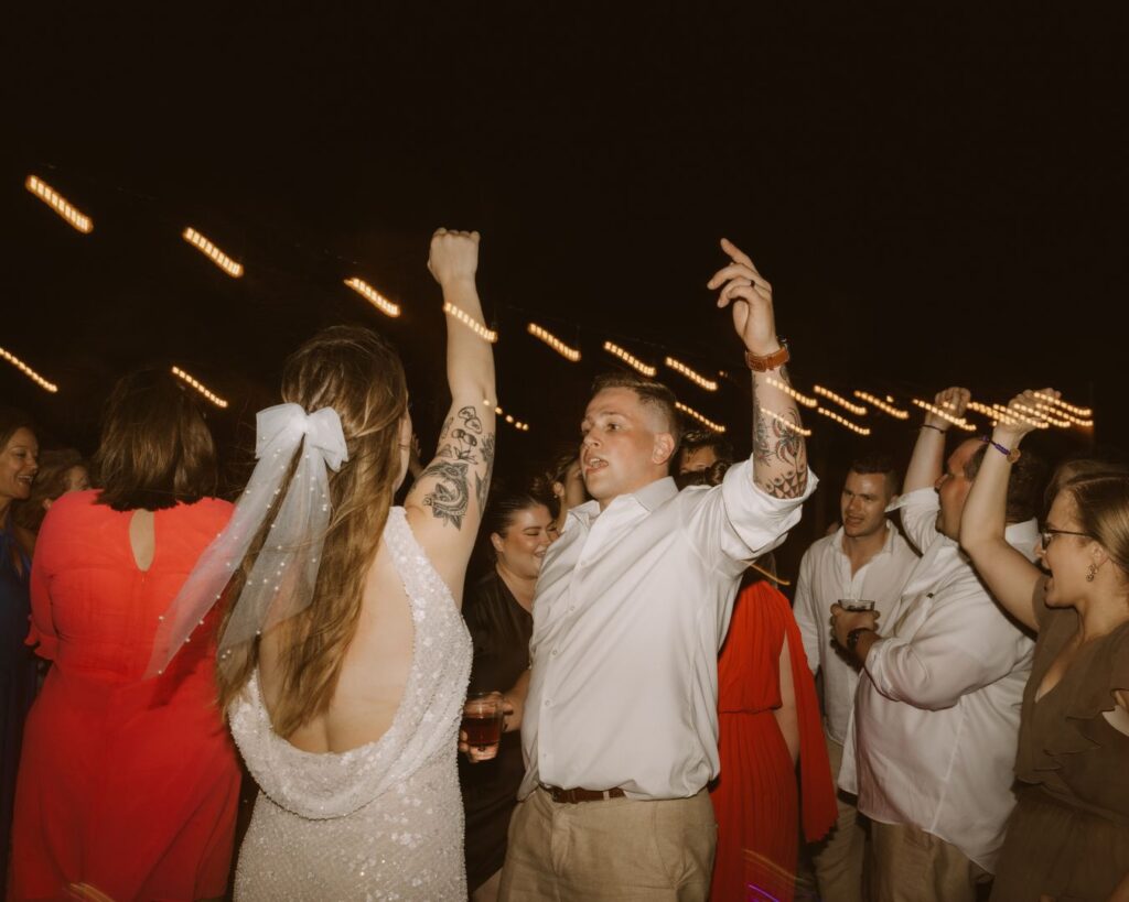 The bride and groom dancing together surrounded by multiple of their guests. 