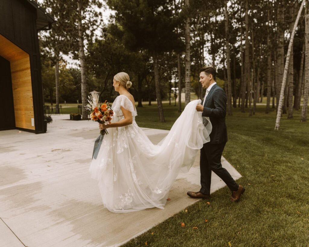 Groom helping carry the brides dress as they make their way up to their wedding venue. 