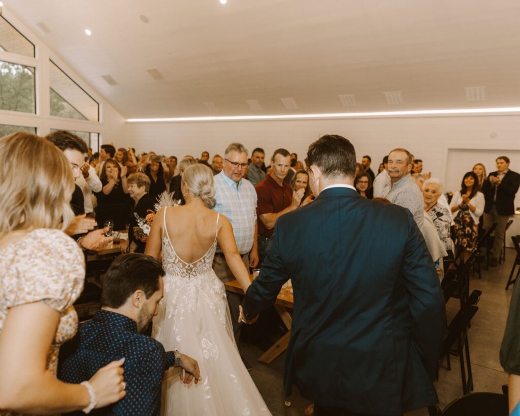 Bride and groom making their way through their guests during the grand entrance to their wedding reception. 