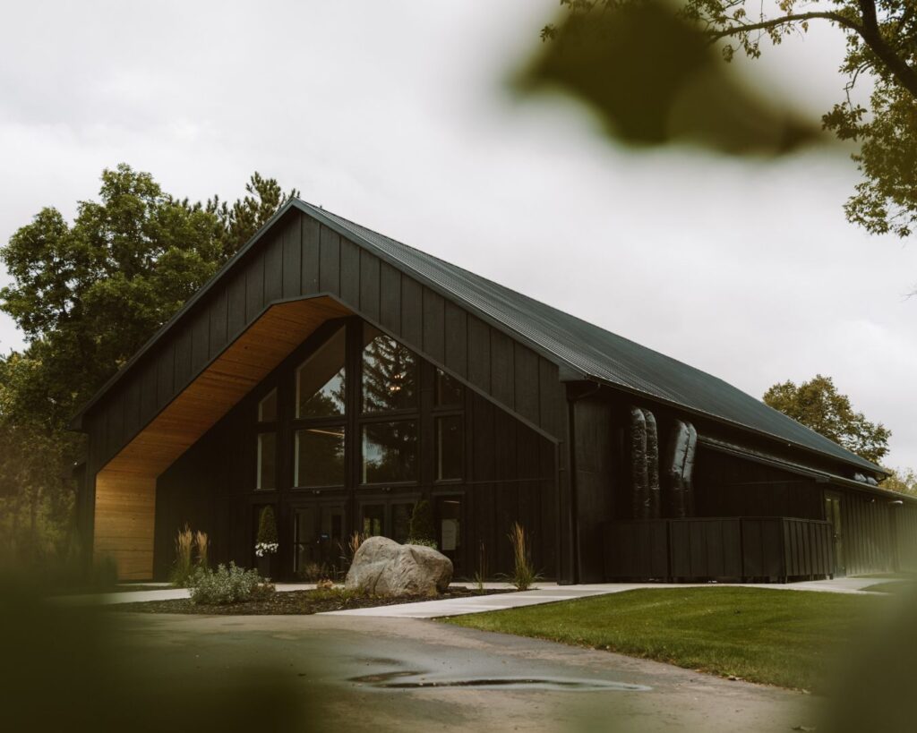 Modern, clean, black and wood wedding venue surrounded by green trees