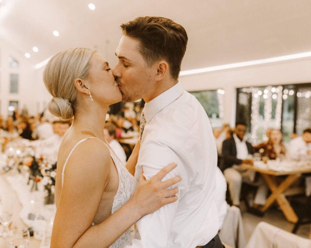 Bride and groom kissing in front of all their wedding guests during their wedding reception.