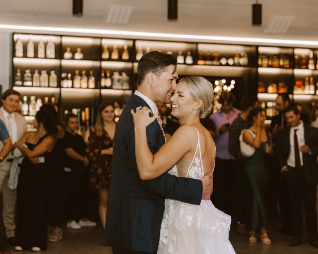 The bride and groom surrounded by their guests, laughing during their first dance.