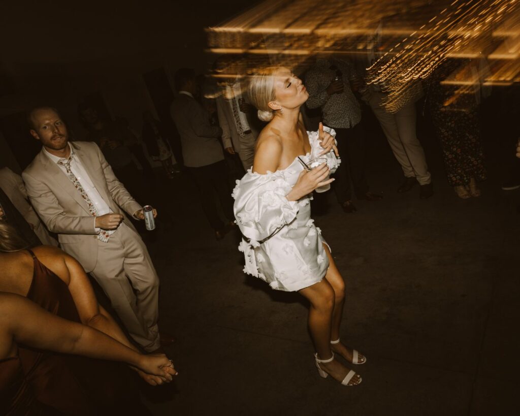 The bride holding a drink and dancing