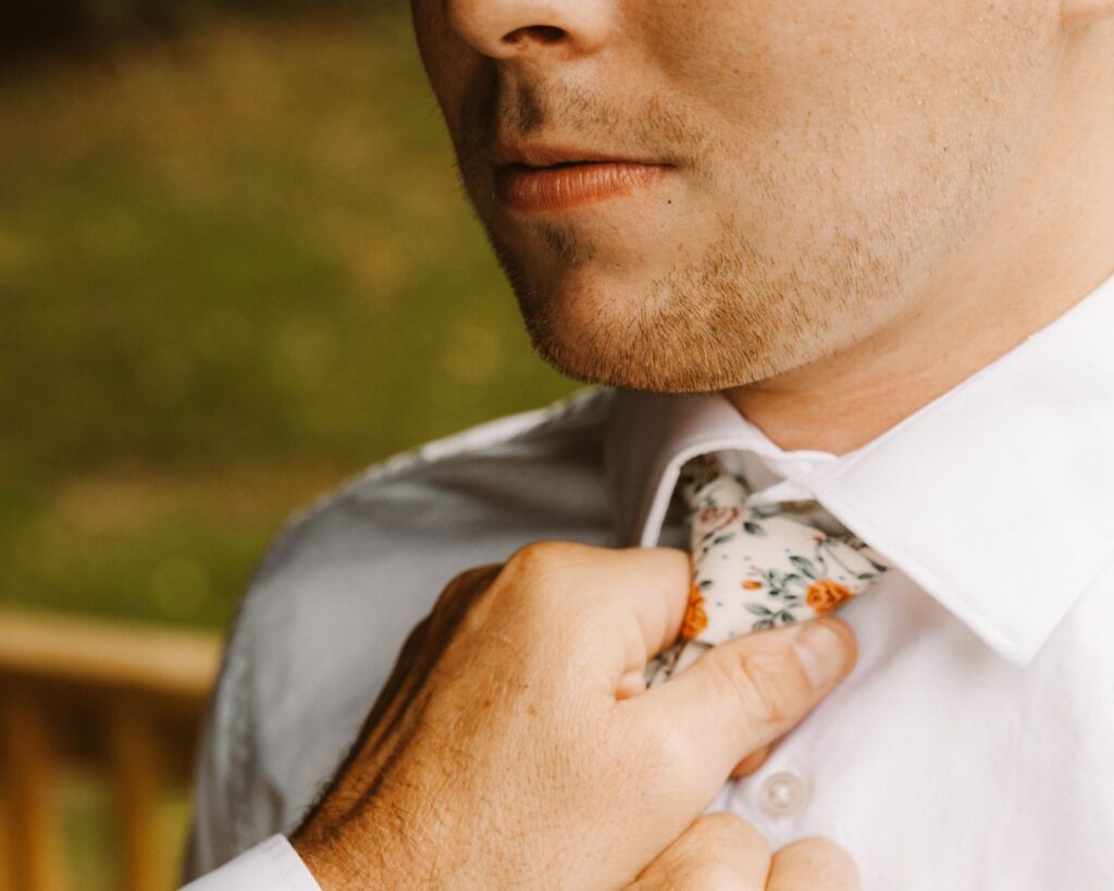 Up close photo of the groom having his tie out on by his father. 