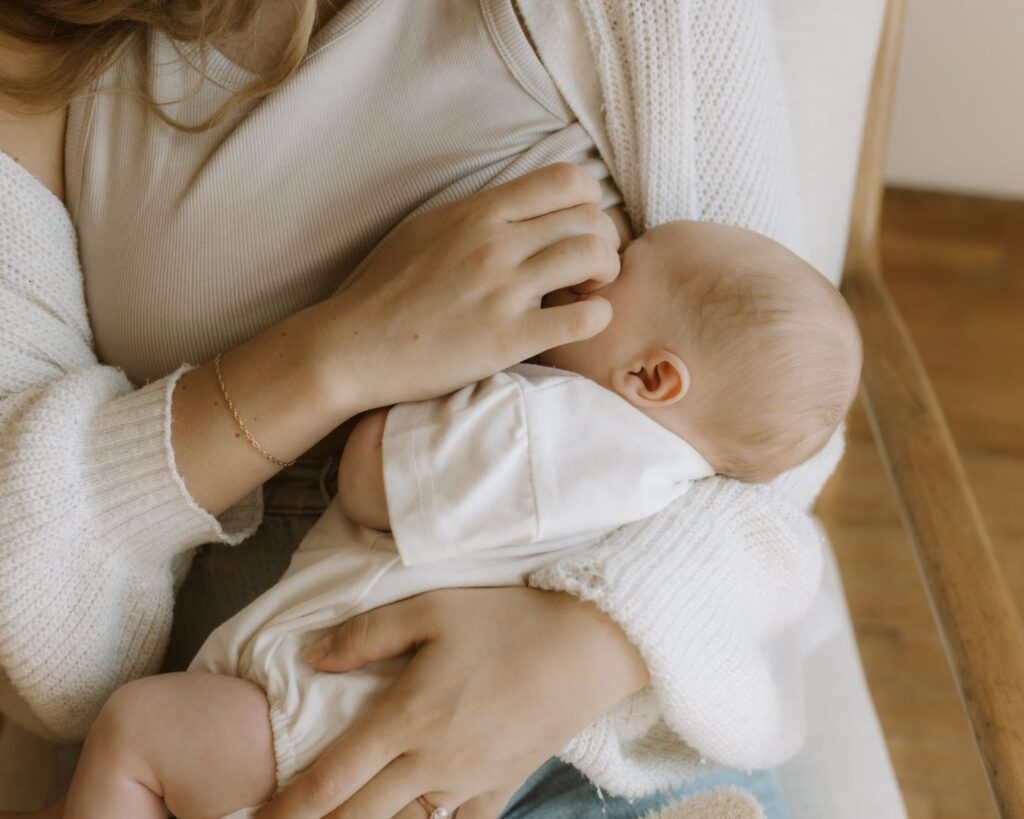 New mom breastfeeds her baby while lightly touching his face