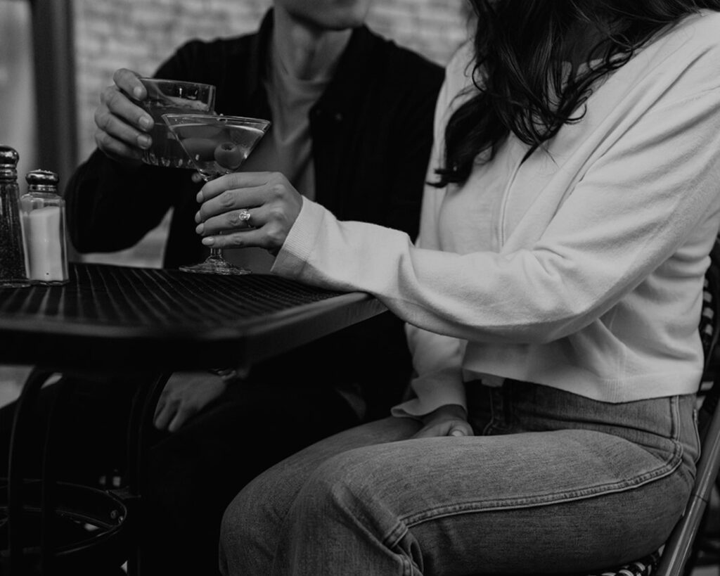 up close image of the bride and groom clinking their drinks, a martini and an old fashioned