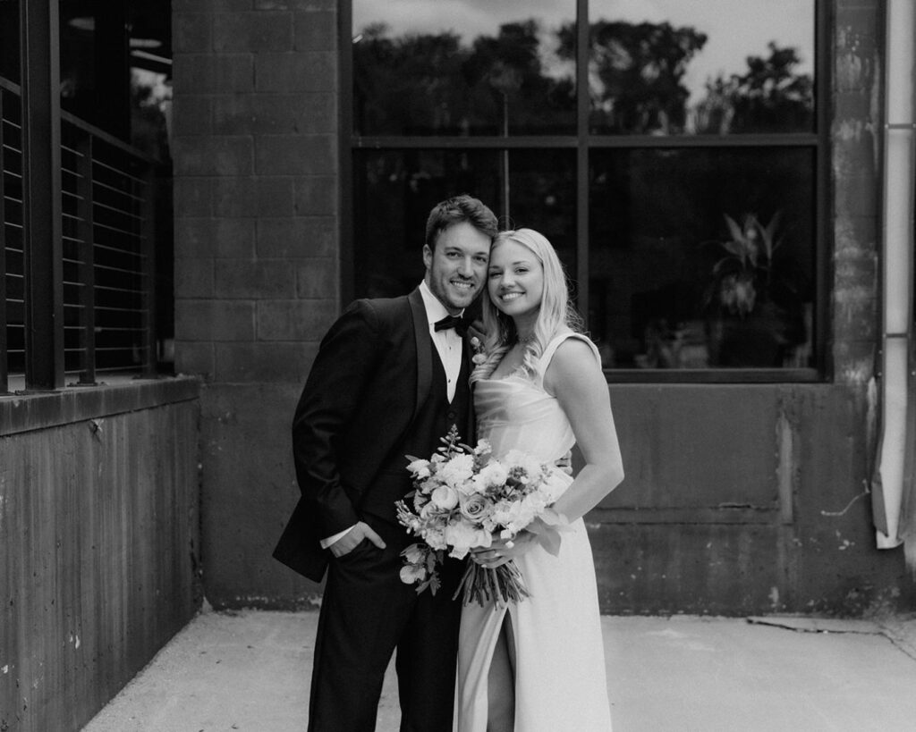 a black and white image of the bride and groom smiling at the camera with heads together