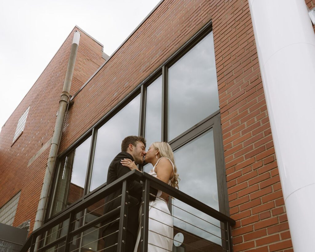 the bride and groom kissing up on the top of the stairs before entering their venue 