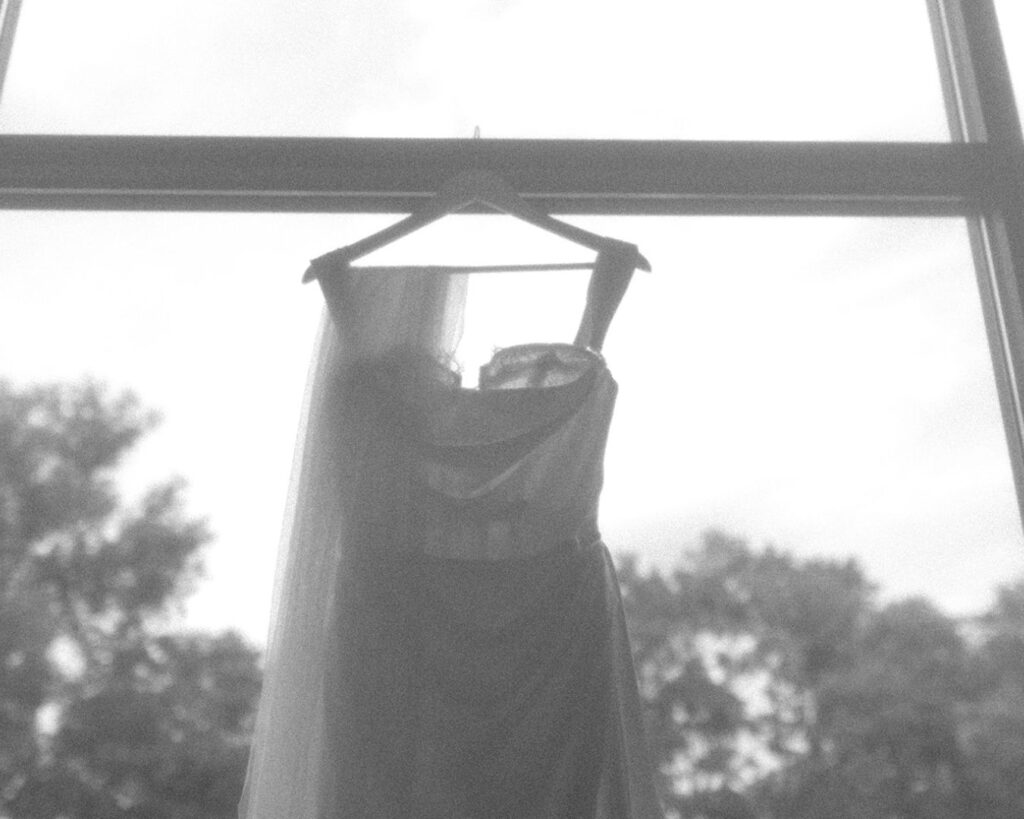 black and white high noise image of the top of the dress and veil hanging from a window 