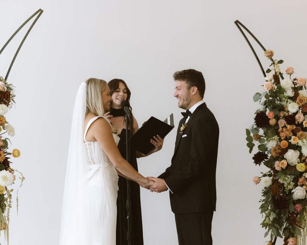 the bride and groom holding hands as they say their vows and a family member officiates their ceremony 