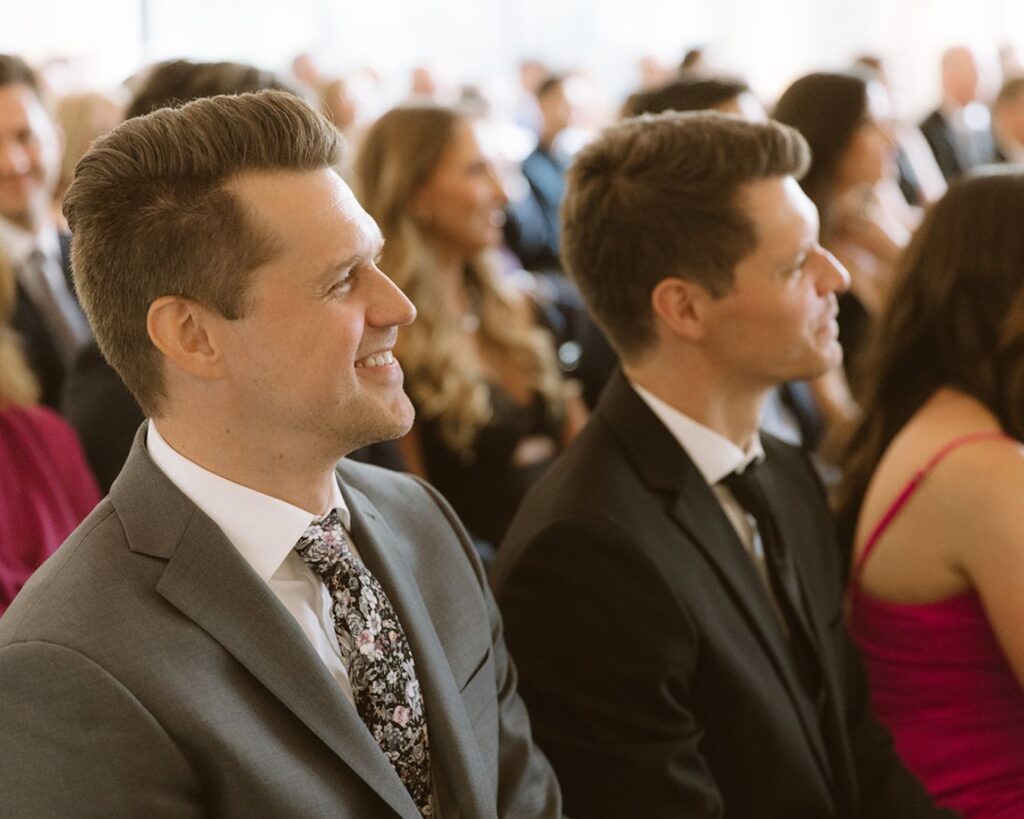 The brides brother's smiling as they watch the ceremony 