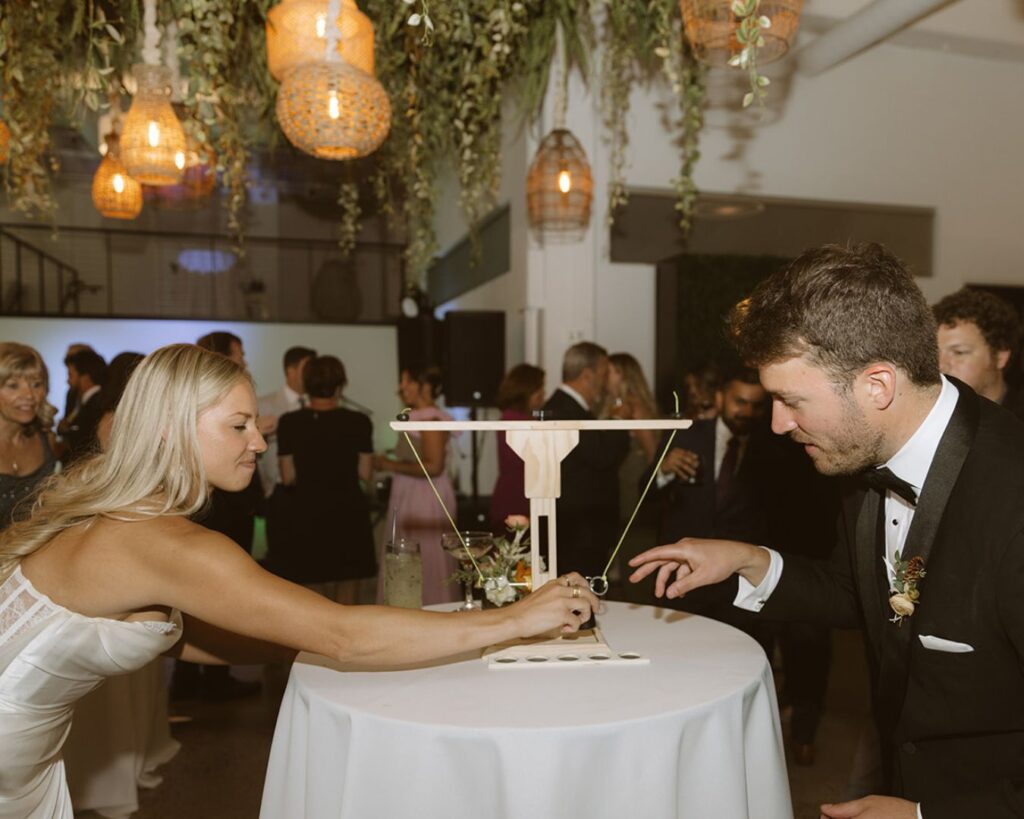 The bride and groom in action playing a game called hook and ring during their cockatil hour