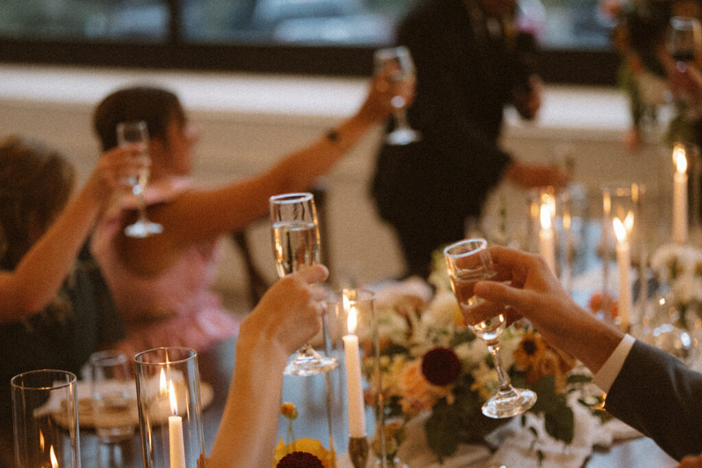 a photo of hands raising champagne glasses in a cheers to the bride and groom 