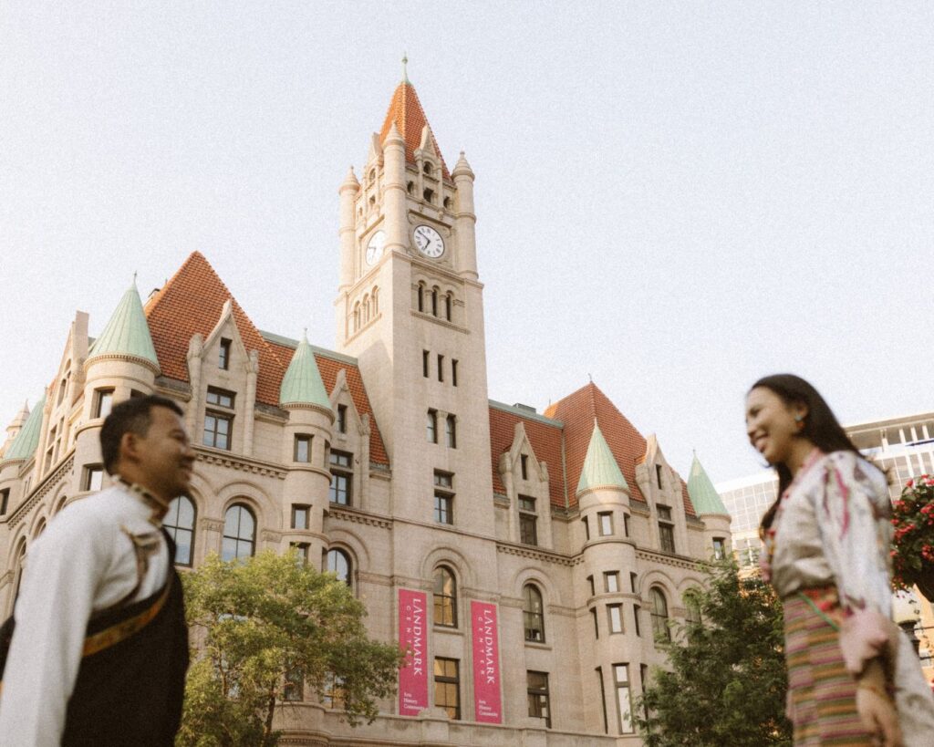 A couple walking towards each other and smiling. They are out of focus and the Landmark center in St. Paul is behind them in focus. 