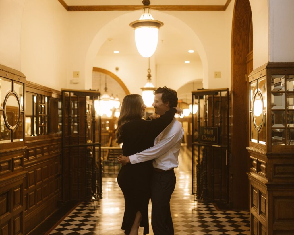 Couple wrapped up in each others arms, laughing just before kissing in the St. Paul Blair Arcade Building. 